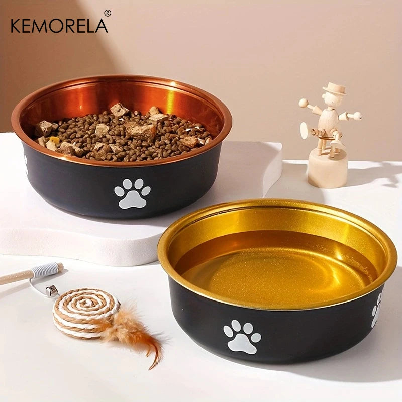 Two black dog bowls with gold interior and white paw prints on white surface