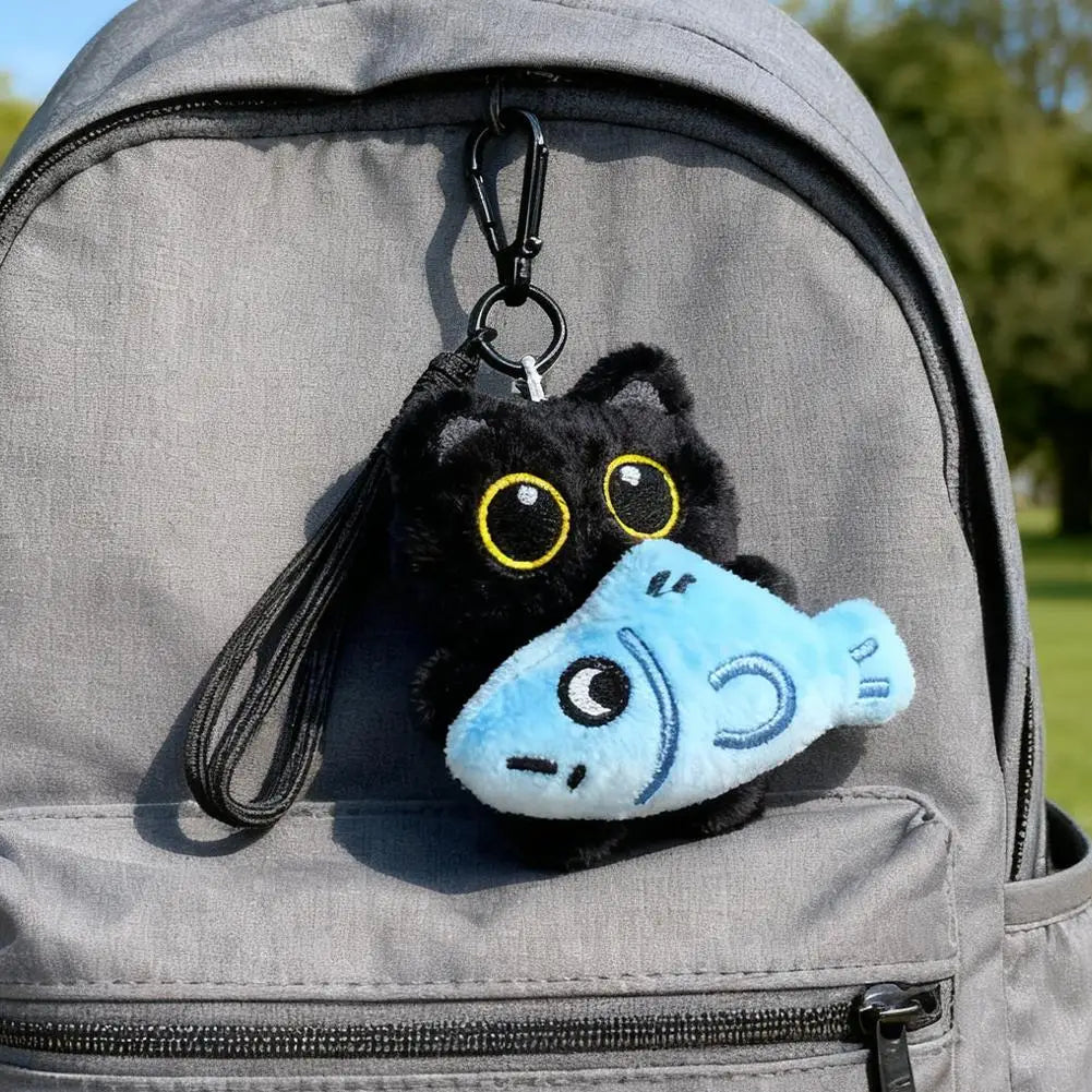 Black plush cat keychain with fish charm on backpack